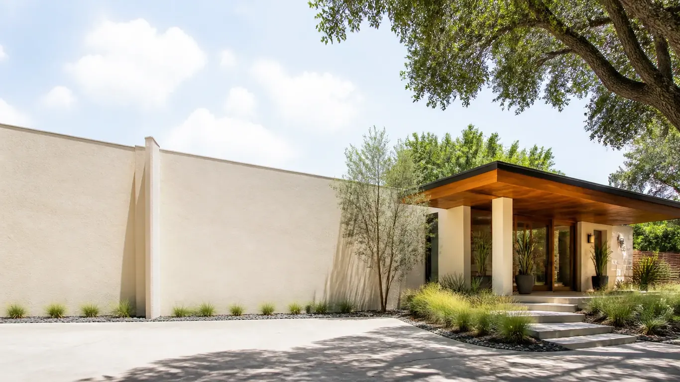 Walled courtyard entry to a modern stucco house with a wood-soffit porch