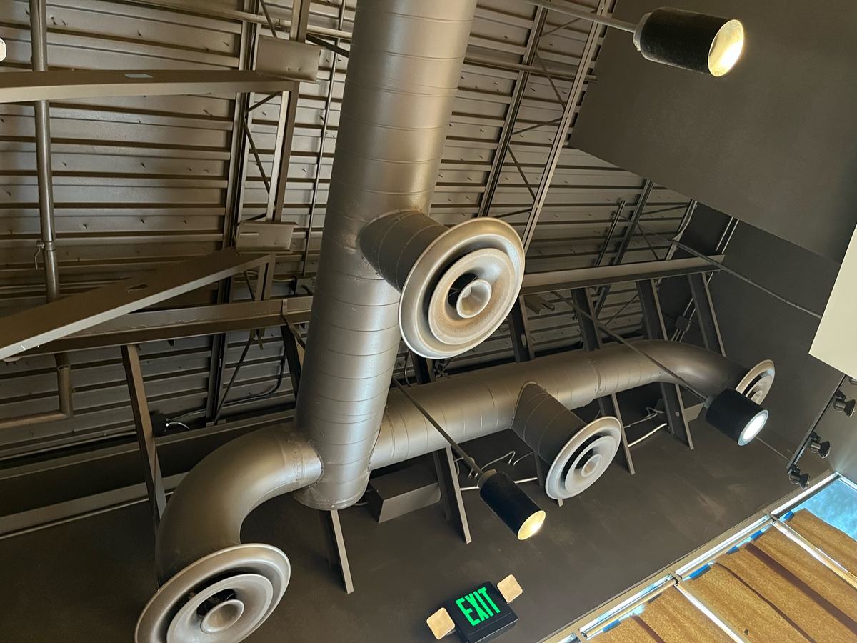 Exposed painted spiral duct with round diffusers in an open commercial ceiling