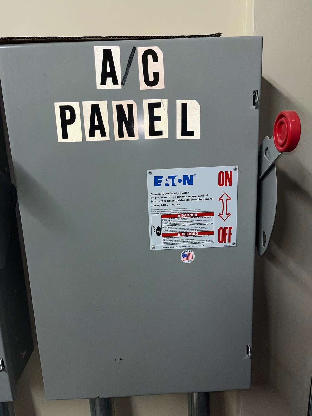 Grey general-duty safety switch labelled A/C PANEL, mounted on an interior wall