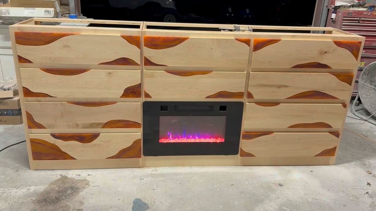 Light-wood cabinet with resin-filled accents and a lit electric fireplace insert