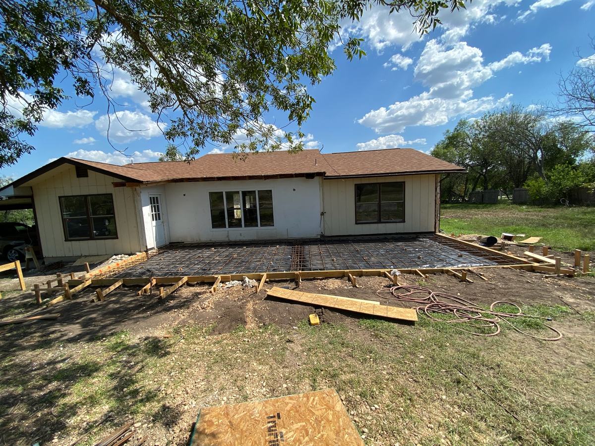 Formed slab with rebar laid out along the back of a single-story house for a new addition