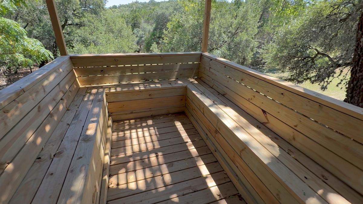 Built-in wood bench wrapping a deck corner with a view over trees