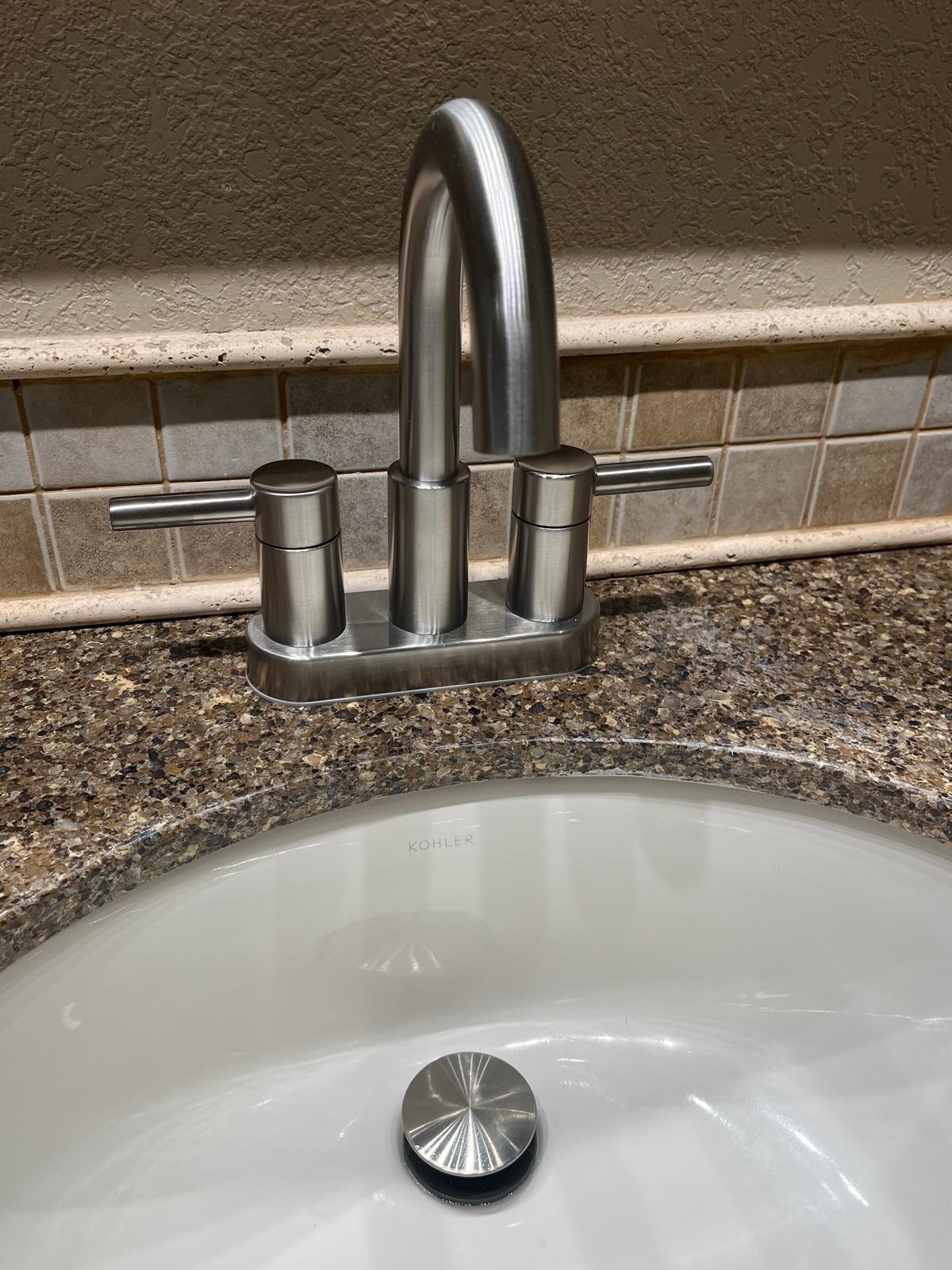 Brushed nickel two-handle bathroom faucet on a granite vanity top with an undermount sink