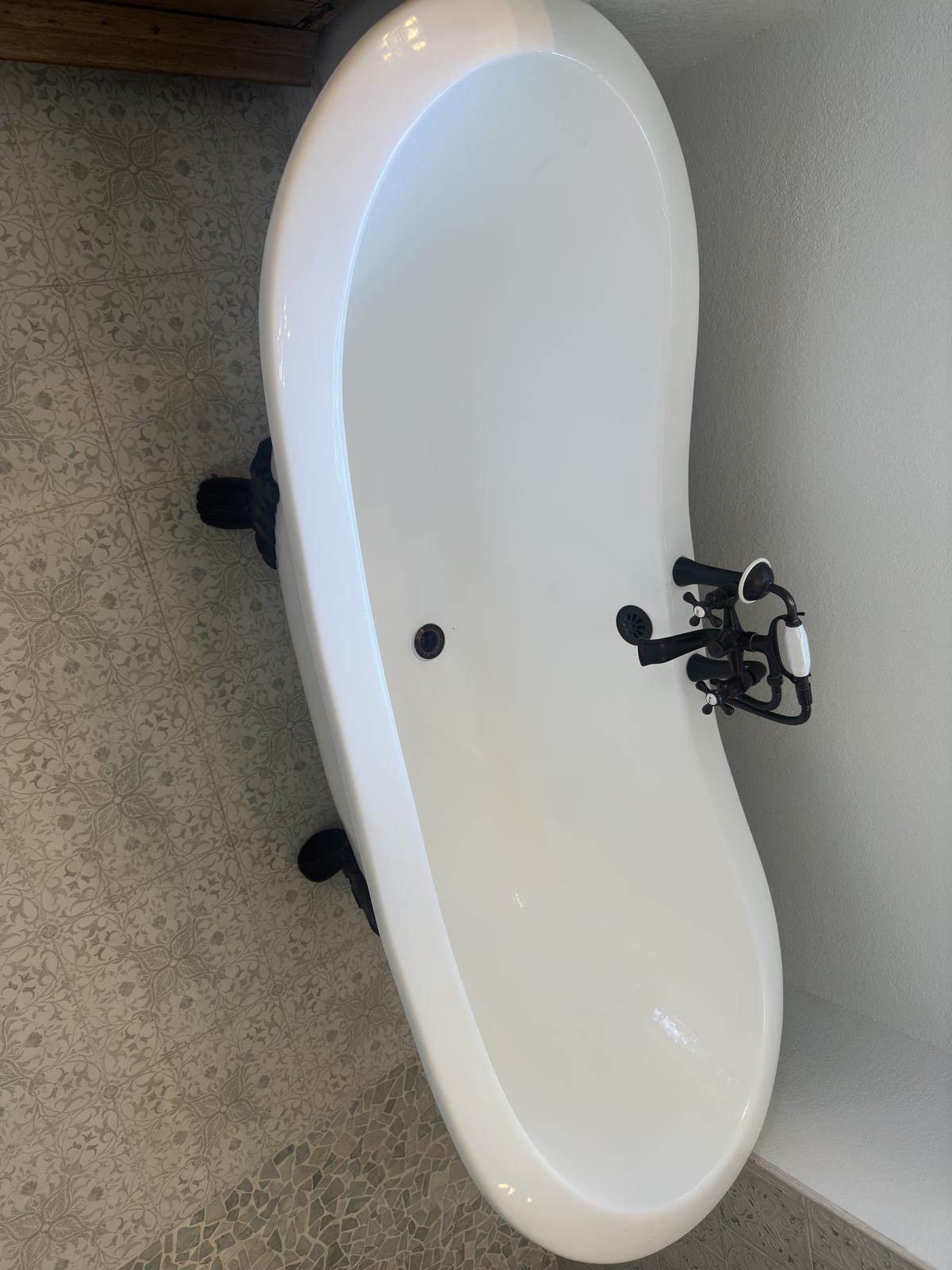 Top-down view of a white clawfoot tub with an oil-rubbed bronze tub filler and handheld shower