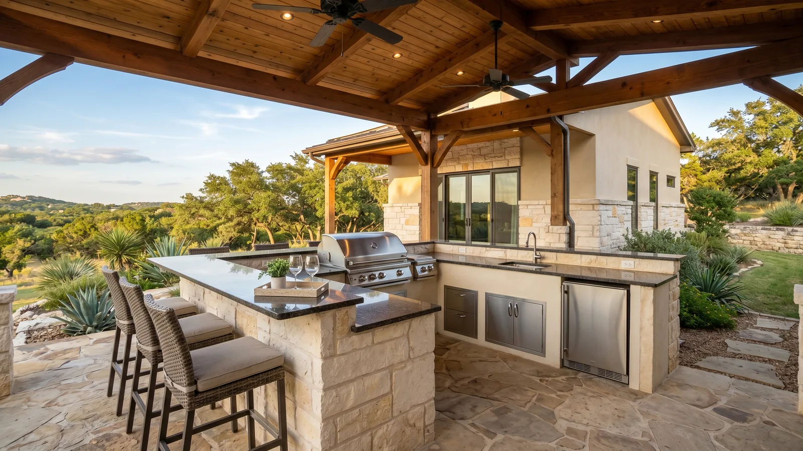 Custom outdoor kitchen with a built-in stainless grill, stone island, and covered patio behind a San Antonio TX home, built by veteran-owned general contractor 214 Veteran Solutions