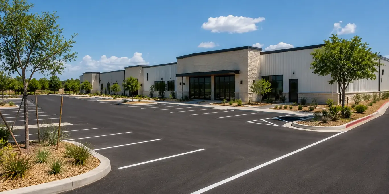 Freshly sealed and striped asphalt car park in front of a new stone-and-metal commercial building; Project planning by veteran-owned 214 Veteran Solutions